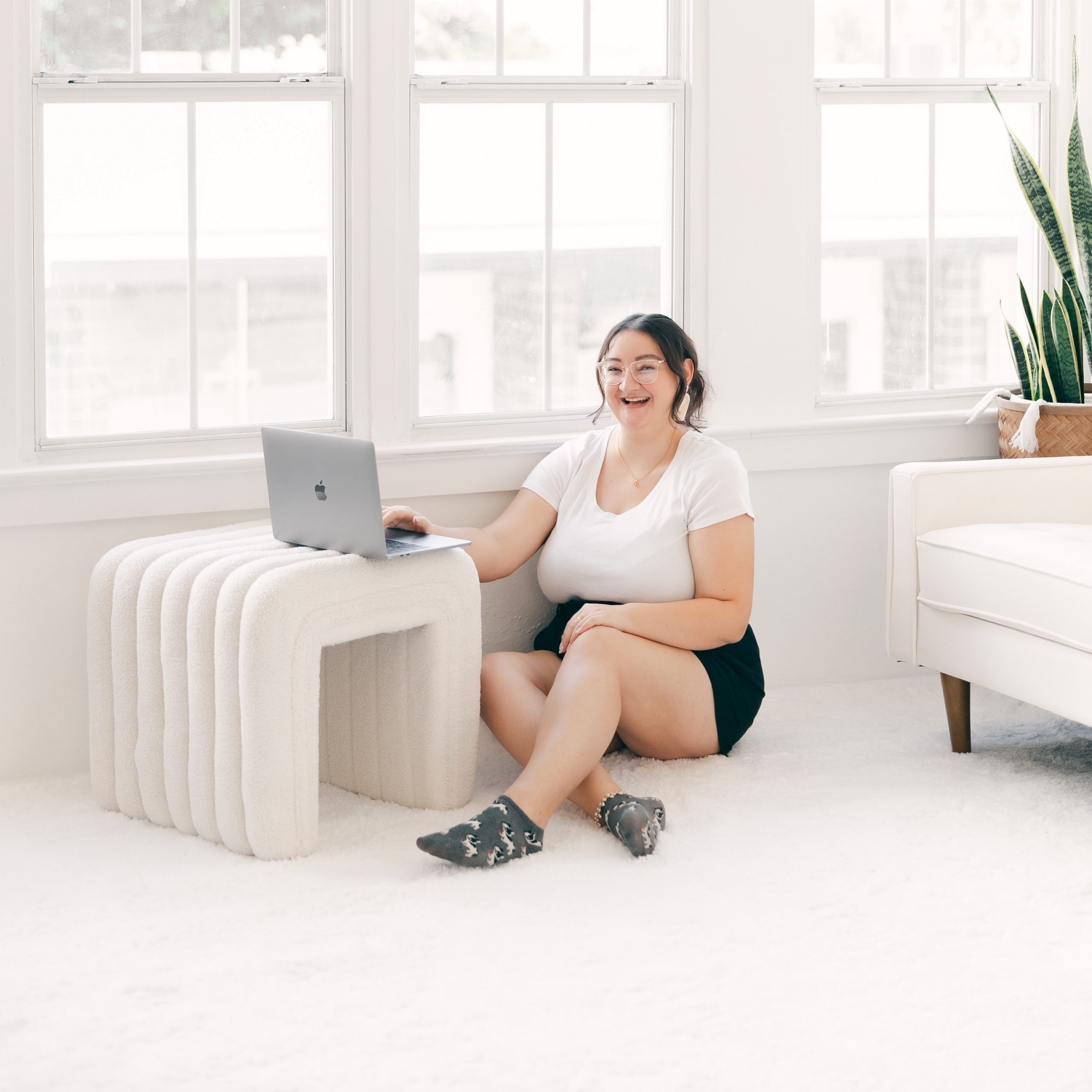 graphic designer sitting on floor working on laptop