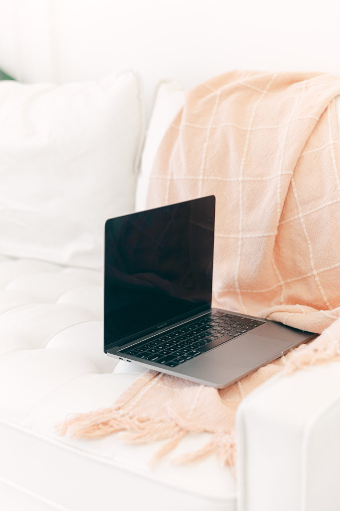 white couch with pink throw blanket and laptop