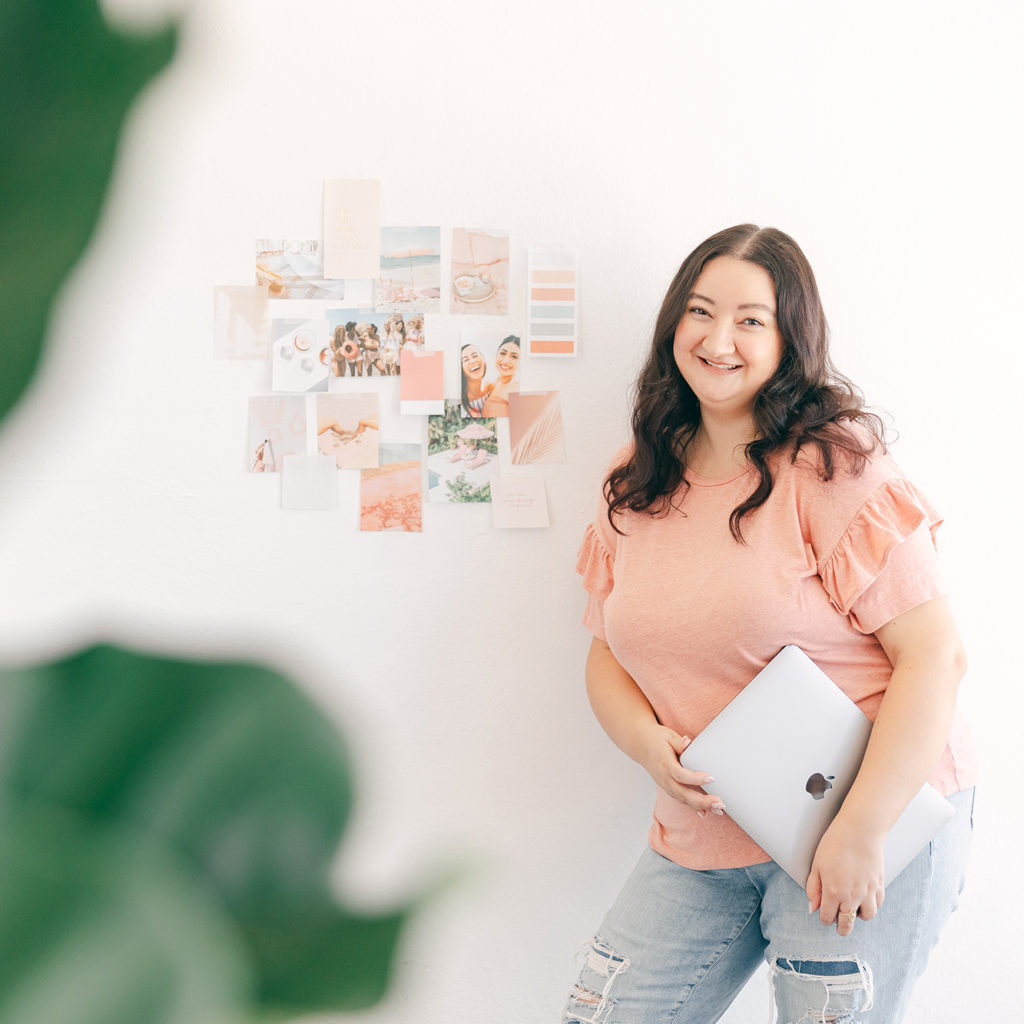 graphic designer holding laptop in studio with brand mood board